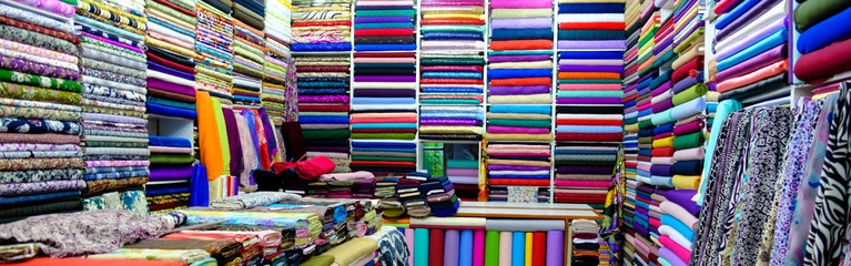 Foto auf Alu-Dibond Kleidung im Laden, Stoffrollen und Textilien zum Verkauf in Regalen im Laden gestapelt, Blick auf Stoffrollen in verschiedenen Farben und Mustern in Regalen im Stoffladen © AMAR