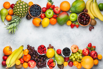 Healthy fruits berries background, strawberries raspberries oranges plums apples kiwis grapes blueberries mango persimmon on the white table, top view, copy space for text, selective focus