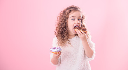 Portrait of a little curly girl eating donuts