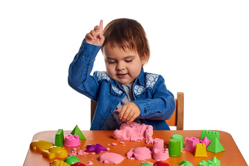 Emotional little child girl playing with kinetic sand on the orange table. Isolated white background