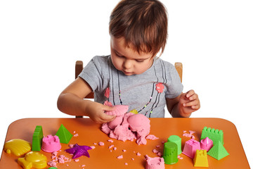 Emotional little child girl playing with kinetic sand on the orange table. Isolated white background