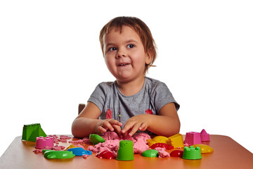 Emotional little child girl playing with kinetic sand on the orange table. Isolated white background