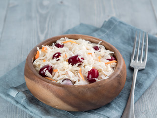 Traditional russian appetizer sauerkraut with cranberry and carrot in wooden bowl on gray rustic wooden table. Fermented cabbage. Russian cuisine and russian kitchen.