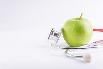 Green Apple with medical stethoscope isolated on white background for healthy eating. Selective focus and crop fragment. Healthy and copy space concept