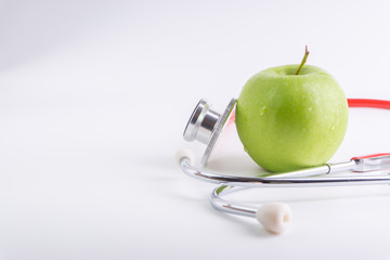Green Apple with medical stethoscope isolated on white background for healthy eating. Selective focus and crop fragment. Healthy and copy space concept