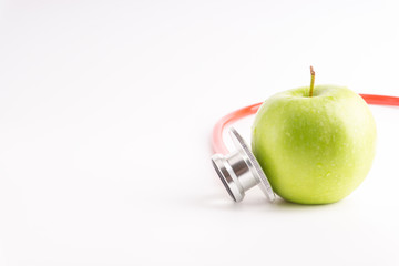Green Apple with medical stethoscope isolated on white background for healthy eating. Selective focus and crop fragment. Healthy and copy space concept