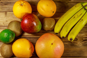 Assortment of tropical fruits on wooden table. Still life with bananas, mango, oranges, avocado, grapefruit and kiwi fruits