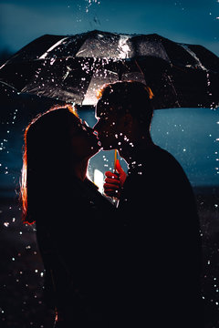 young man and woman under an umbrella and rain