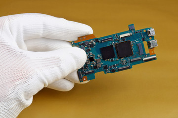 A technician controls the quality of a modern printed circuit board for digital camera
