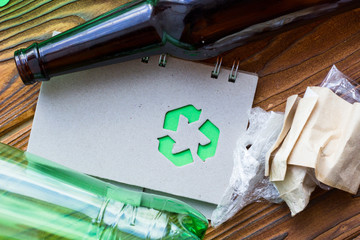 Environmental protection, ecology and recycling concept, recycle sign, notepad and garbage on dark wooden background