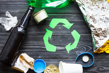 Environmental protection, ecology and recycling concept, recycle sign and garbage on dark wooden background