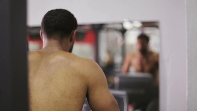 Afro-american male model is training opposite a mirror.