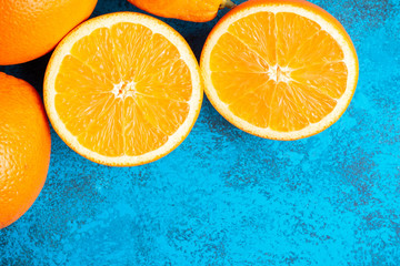 Orange halves and whole ripe citrus fruits on a blue background, top view