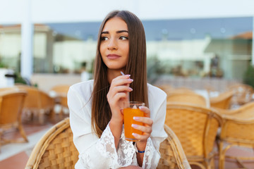 Beautiful young woman sitting in bar cafe, drinking fruit cocktail on a tropical beach. Summer vocation