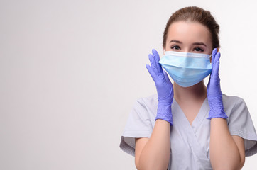 Beautiful female doctor or nurse wearing protective mask and latex or rubber gloves on grey background with copyspace. Health care concept