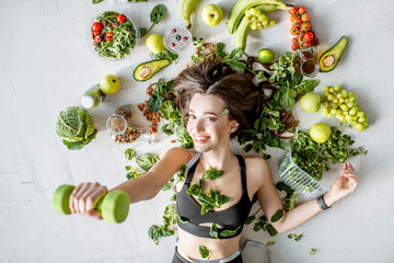 Beauty portrait of a sports woman surrounded by various healthy food lying on the floor. Healthy...