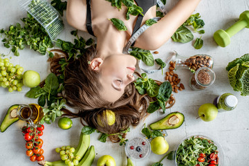 Beauty portrait of a woman surrounded by various healthy food lying on the floor. Healthy eating...