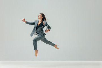 Happy business woman dancing and smiling in motion isolated over white studio background. Human...