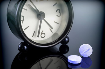 Blue pills next to a clock, conceptual image
