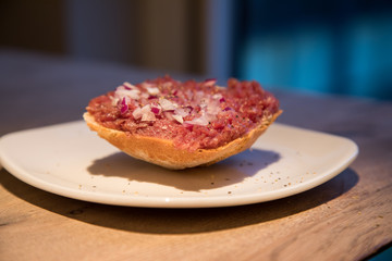 Teller Beef Tatar Mettbrötchen mit Rindfleisch und Zwiebeln auf Holz Tisch