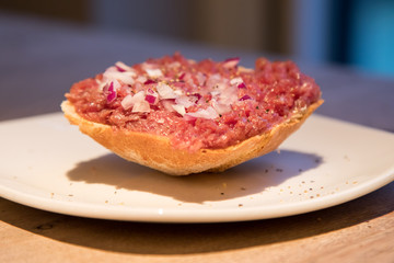 Teller Beef Tatar Mettbrötchen mit Rindfleisch und Zwiebeln auf Holz Tisch