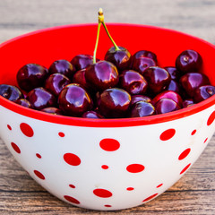 Berries of a sweet cherry on a wooden background in a plastic cu