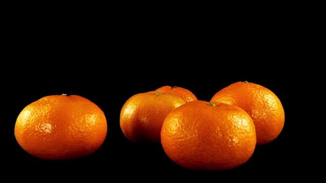 Tangerines on a black background.	Shooting in the movement.