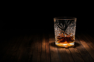 Crystal glass of whiskey on a wooden table on a black background. Snack for whiskey. Cheese, almonds, pear, apple, olives, orange peel. - obrazy, fototapety, plakaty