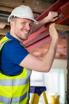 Construction Worker Fitting Steel Support Beam Into Renovated House Ceiling