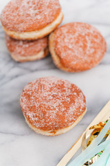 Traditional German or Austrian fried donuts with no hole, so called Krapfen, Berliner or Pfannkuchen with cinnamon sugar and filled with rose hip, raspberry or strawberry jam, party or carnival food