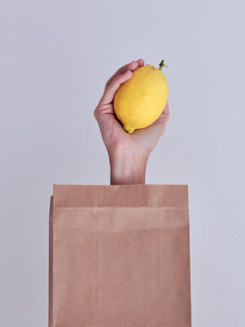 Person hand reached out from packet and holding lemon