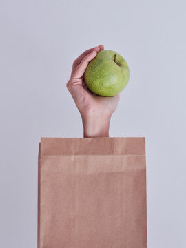 Person hand reached out from packet and holding apple