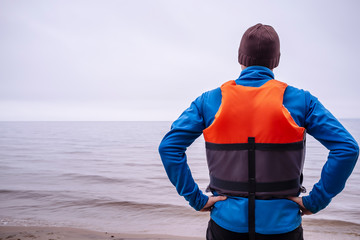 person in life jacket lies a sandy beach on the lake
