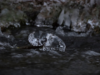 smooth motion of wild water in a river in winter with snow and ice on rocks and stones in the beautiful nature of a forest