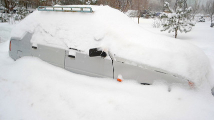 Snow on cars after snowfall. Car under snow after heavy snowstorm. Winter urban scene.