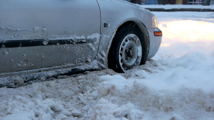 Passenger car stalled on snowy road. Car stuck in the snow after heavy snowstorm, cropped image....