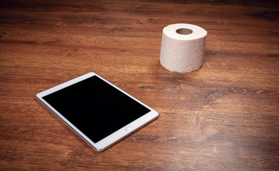 Old tablet pc with toilet paper on wooden background