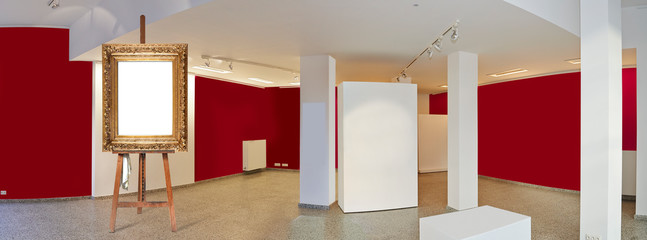 Painter's easel and empty antique golden frame in a exhibition gallery