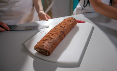 There is a delicious chocolate roll on the table and the children have just baked it in a cooking class.