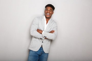 happy young african american businessman laughing with arms crossed against gray background