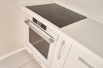 Modern white kitchen with induction cooktop. Induction stove in white modern kitchen. Contemporary kitchen design.