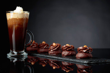  Chocolate dessert with hazelnut and coffee with cream on a black background.