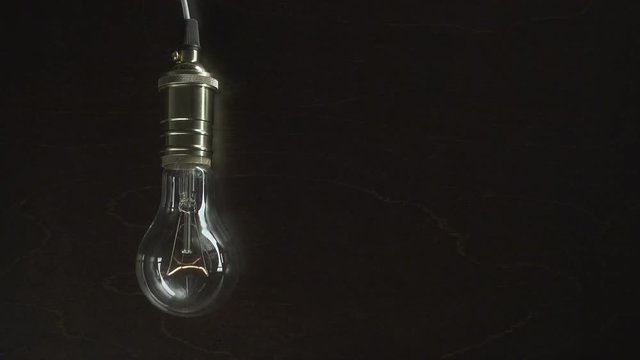 The light bulb slowly lights up, quickly flickers on a background from a wood