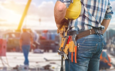 Fototapeta na wymiar Male worker with tool belt on background