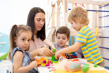 Educator teaches children handcraft at kindergarten or playschool