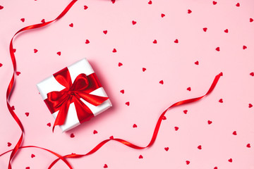 Pink holiday Valentine's background with present gift box and little hearts on background. Valentine's day greeting concept. Top view, flat lay.