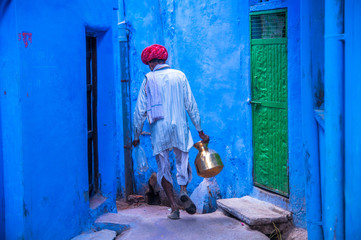 Man wearing traditional clothing walking in blue street, Bundi, India