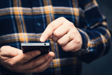 hipster man holding smartphone and tapping on the screen