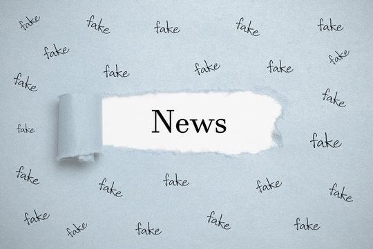 Papierriss zeigt das Wort "News" umgeben von vielen "fake" Wörtern 