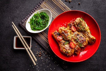 The concept of Japanese and Chinese cuisine. Chicken fried legs with hot pepper, sesame, chuka salad, Chinese peas on black table. Asian dish. top view, flat lay